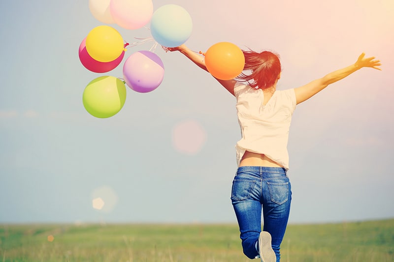 young woman running with balloons